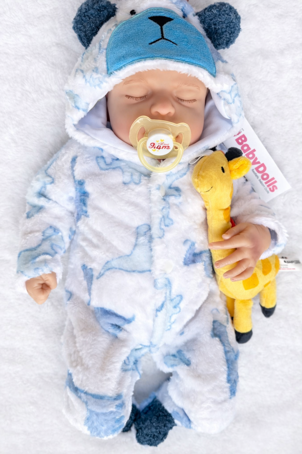 Newborn baby in a blue and white outfit with a yellow toy and pacifier on a white background
